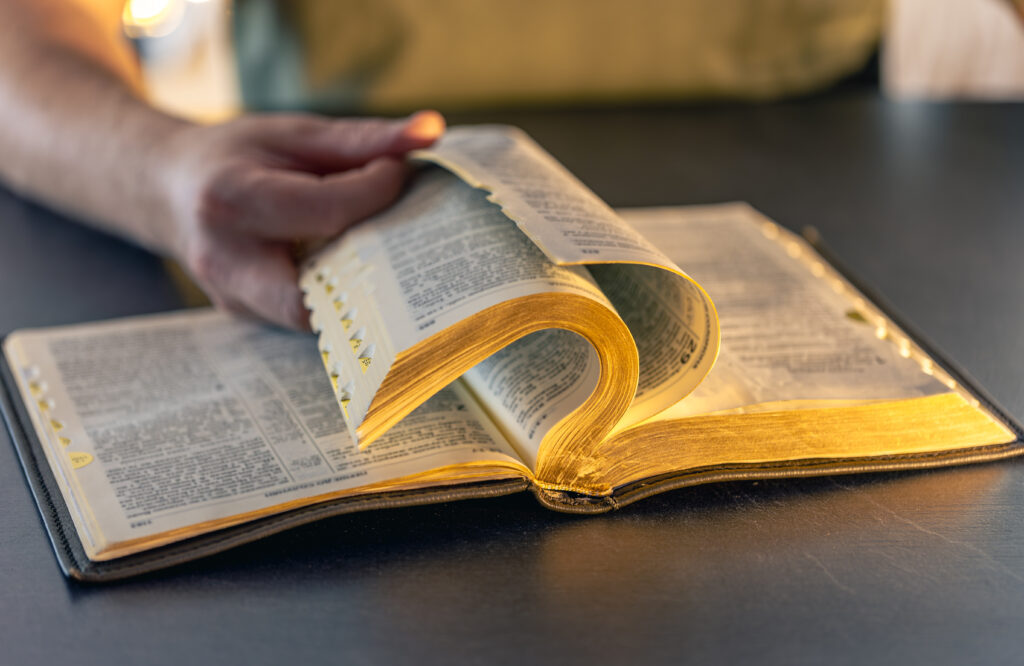 A man reads the Bible. Male hands on the Holy Bible. Close-up of the Bible.